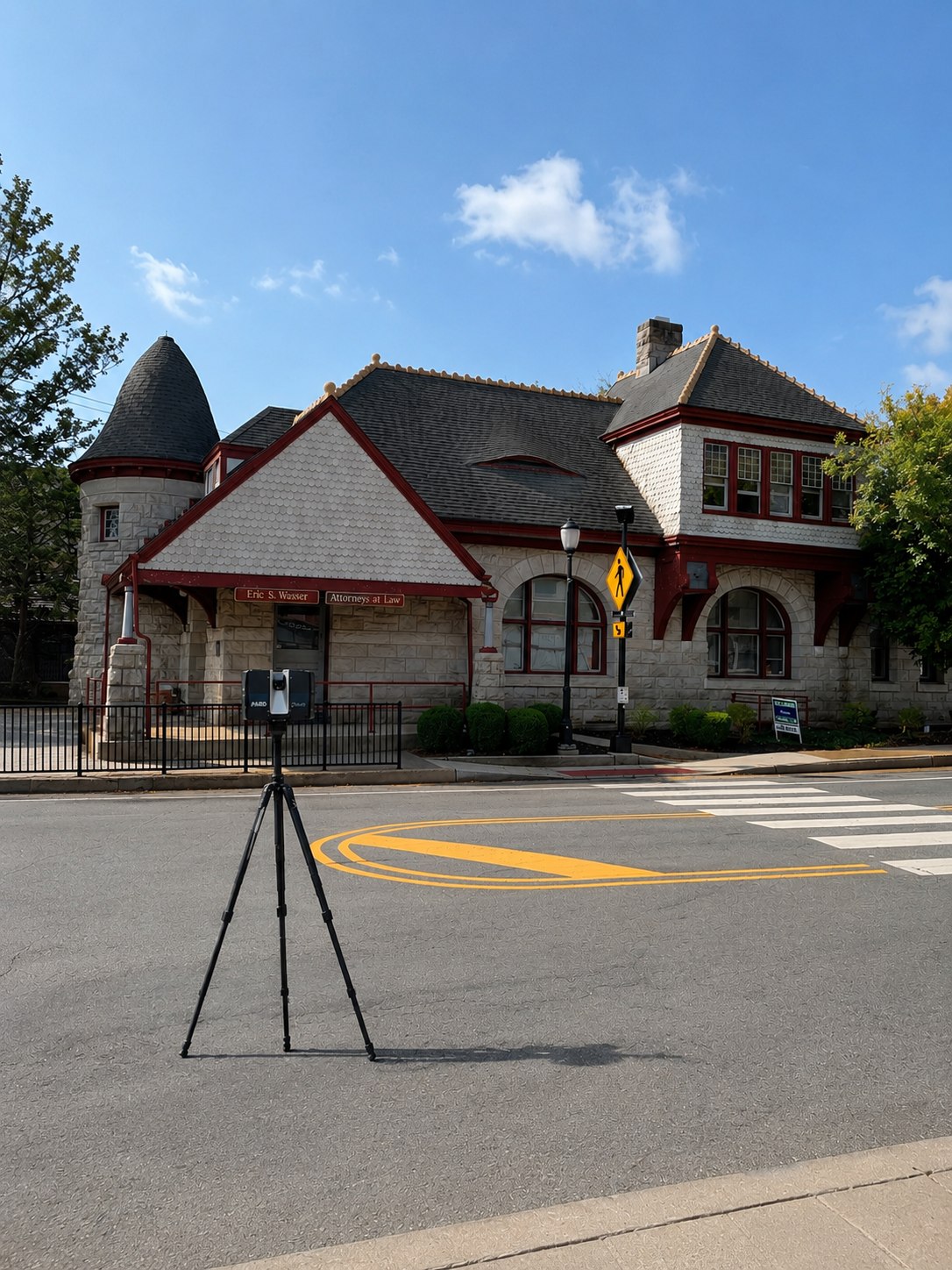 FARO laser scanner on a tripod in front of the historic Somerville Train Station, a stone building with a conical turret and red trim
